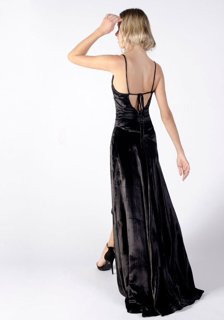 A floor-length black velvet gown with a plunging neckline, long sleeves,  and a flowing skirt. accessorized with a statement pearl necklace and  matching drop earrings on Craiyon